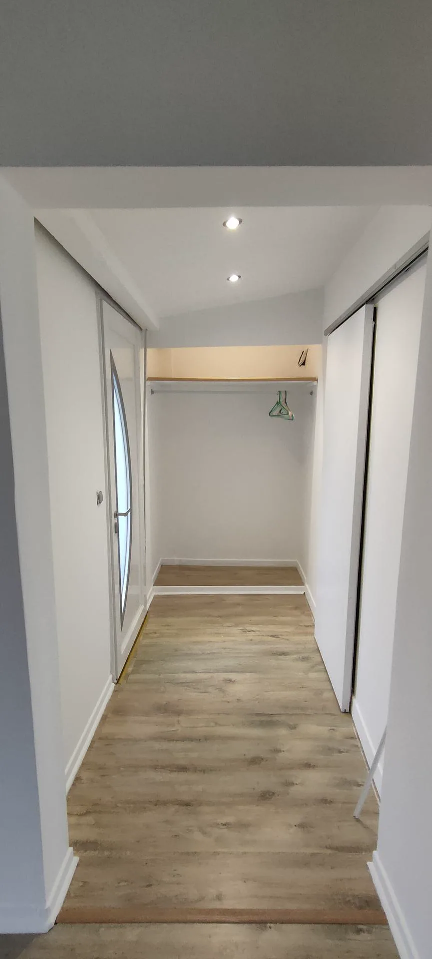 Couloir rénové aux murs blancs et sol aux tons bois