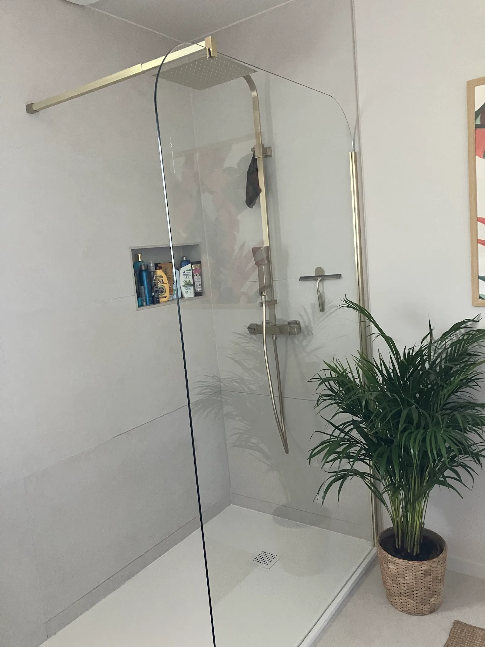 Salle de bain rénovée avec douche vitrée et murs aux finitions claires